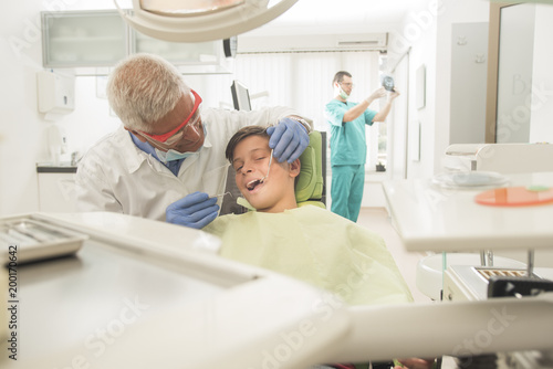 Boy with perfect teeth at the dentist doing check up with the clinic at the background - oral hygiene health care concept