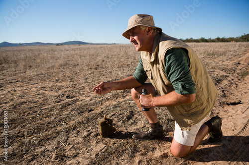 Man with binocular kneeling on landscape photo