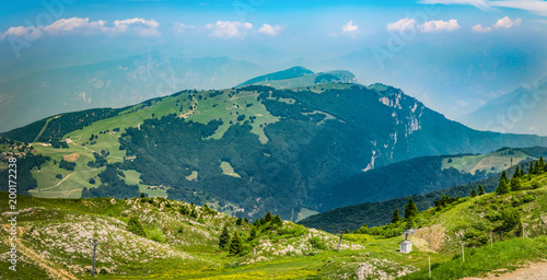 Fototapeta Naklejka Na Ścianę i Meble -  Panoramic view landscape in Dolomite Alps, Italy, with fresh green meadows and blooming flowers and mountain tops in the background.Panorama of Monte Baldo, European Alps on a sunny day with blue sky