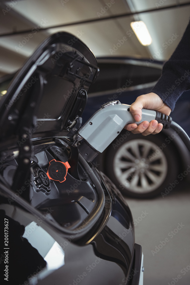 Man charging car at electric vehicle charging station Man charging car at electric vehicle charging station