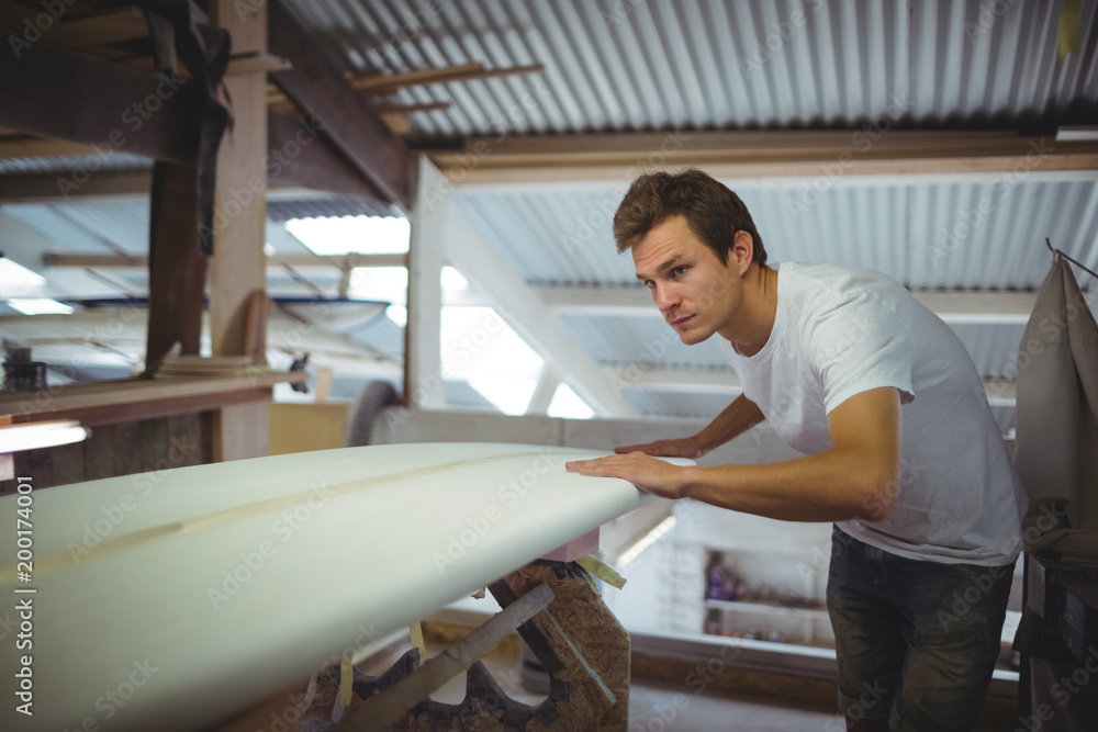 Man working on surfboard in workshop Man working on surfboard in workshop