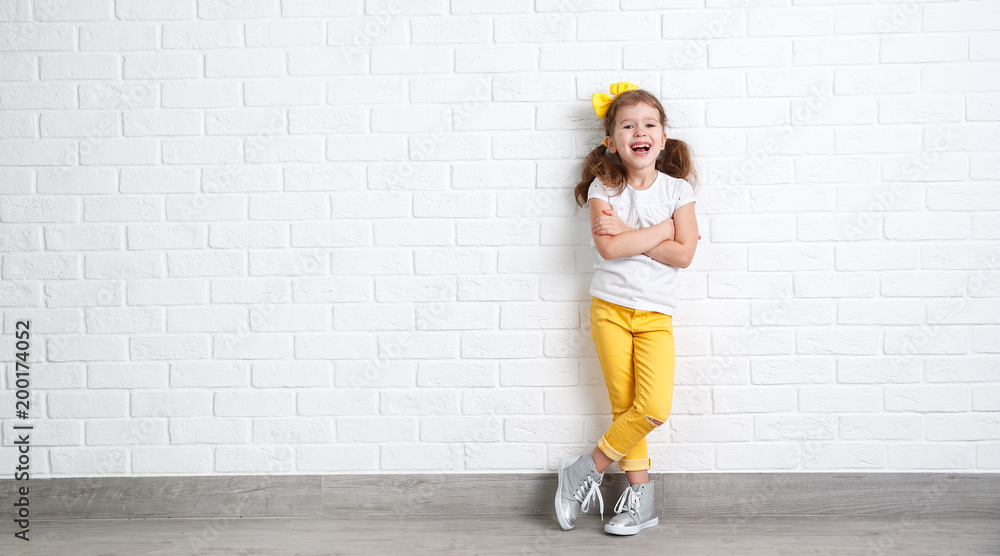 happy funny child girl near an empty brick wall. happy funny child girl near an empty brick wall.