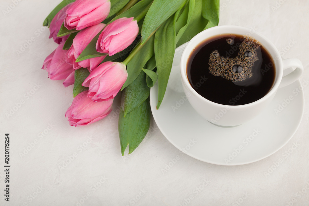 Black coffee in white Cup with pink tulips on light stone background. Top view with copy space Black coffee in white Cup with pink tulips on light stone background. Top view with copy space