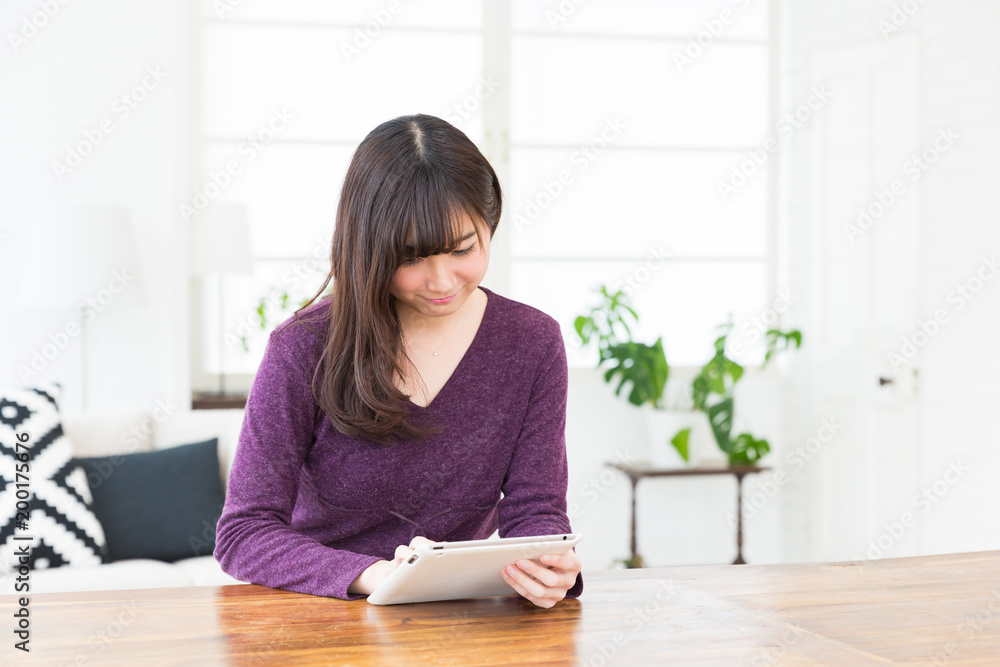 部屋でタブレットを見る女性
