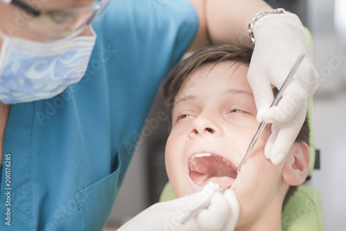 Boy with perfect teeth at the dentist doing check up with the clinic at the background - oral hygiene health care concept