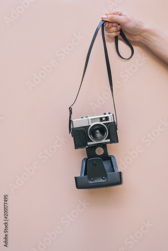 Hand holding a Vintage camera isolated at pink wall