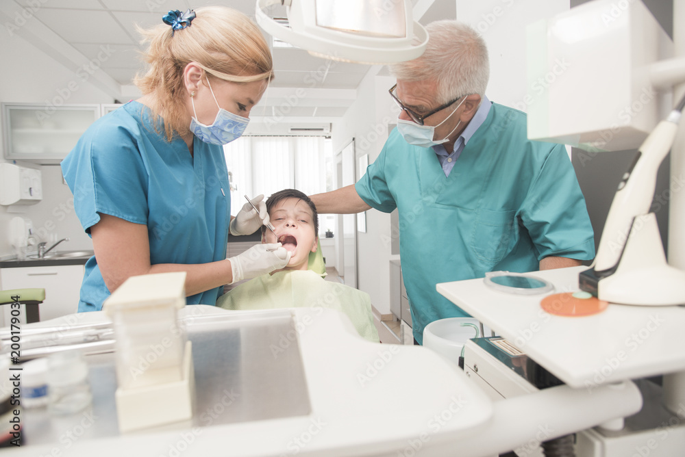 Boy with perfect teeth at the dentist doing check up with senior doctor attending - oral hygiene health care concept Boy with perfect teeth at the dentist doing check up with senior doctor attending - oral hygiene health care concept