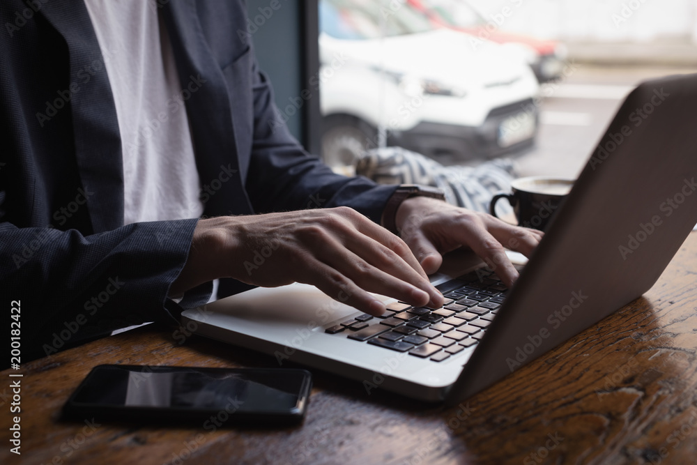 Mid section of man using laptop in cafe Mid section of man using laptop in cafe