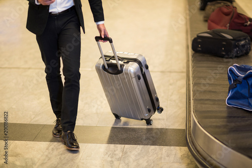 Businessman walking with luggage near baggage claim area photo