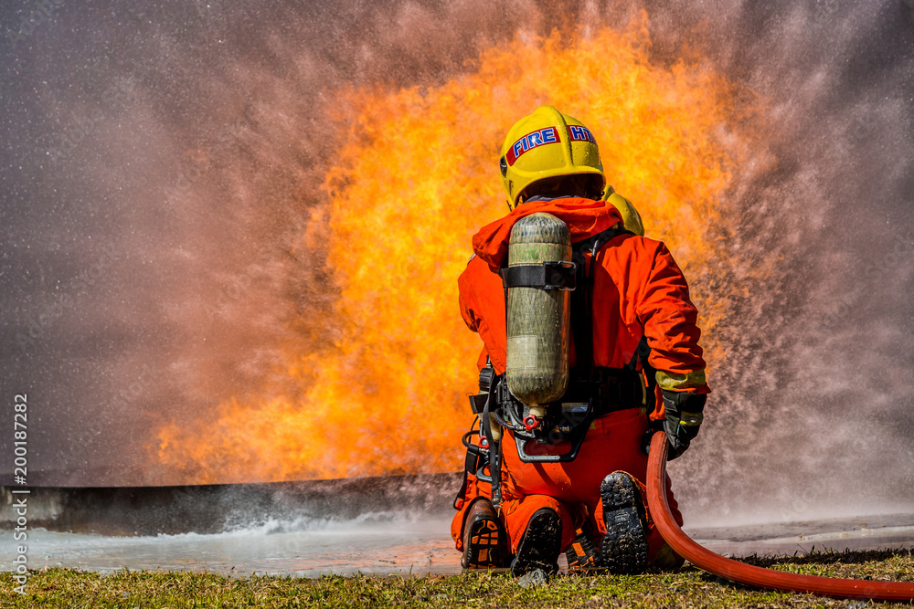 Firefighter using extinguisher and water from hose for fire fighting, Firefighter spraying high pressure water to fire with copy space. Firefighter using extinguisher and water from hose for fire fighting, Firefighter spraying high pressure water to fire with copy space.
