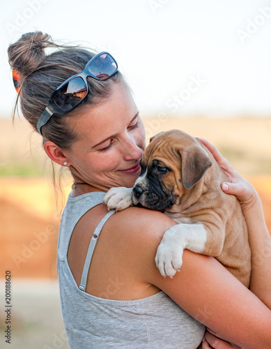 Obraz na plátne Young happy girl holding a cute American Staffordshire Terrier Puppy in her arms