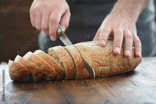 male hands chopped fresh bread wooden table