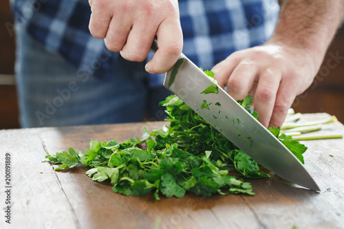 Fényképezés Close up male hands chopping fresh parsley