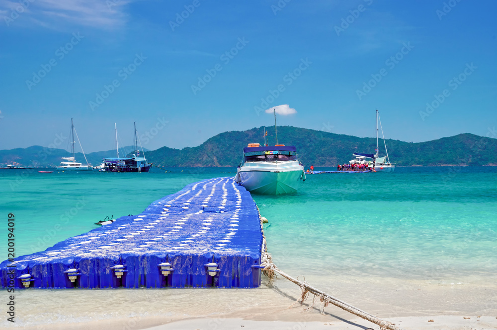 Speed boat at the pier of modular plastic pontoons. Tropical bay seascape with turquoise water and blue sky.