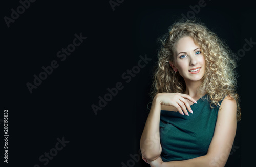 Blonde girl with long and shiny curly hair . Beautiful pretty woman model with curly hairstyle . Copy space for your text