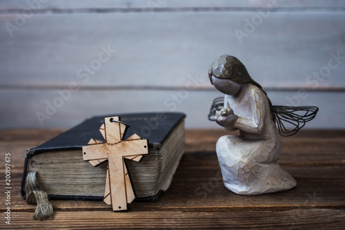 angel old bible and cross on wooden background