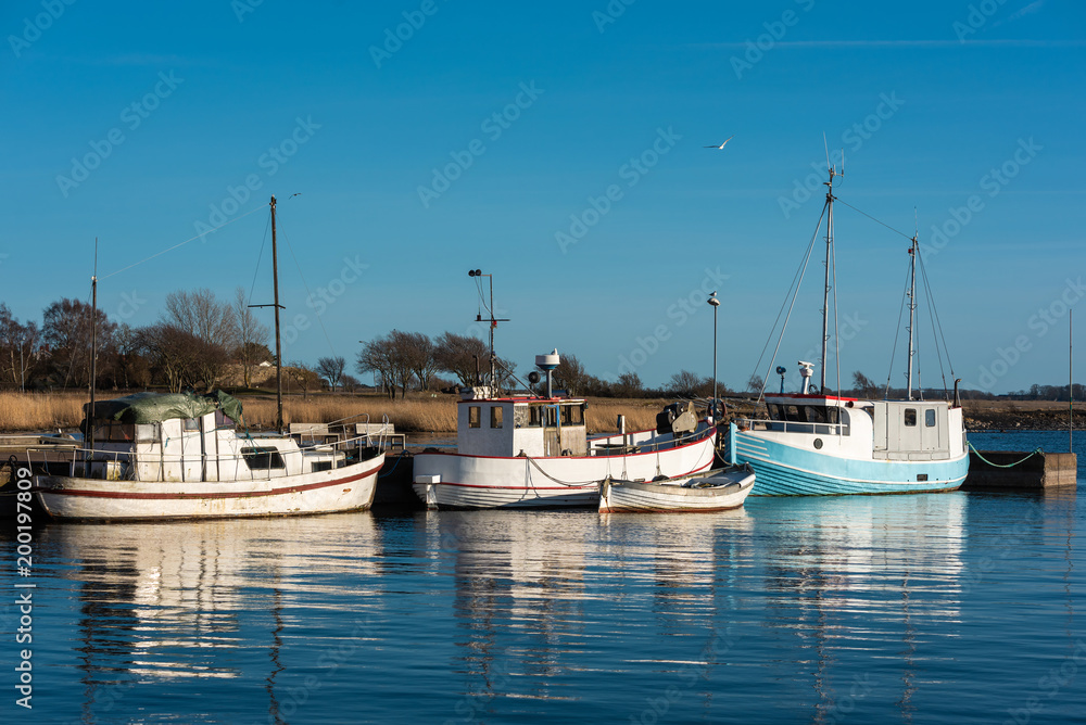 Obraz premium Old and well used fishing boats moored in harbor on a spring evening in Gronhogen on Oland, Sweden. Names and logos removed.