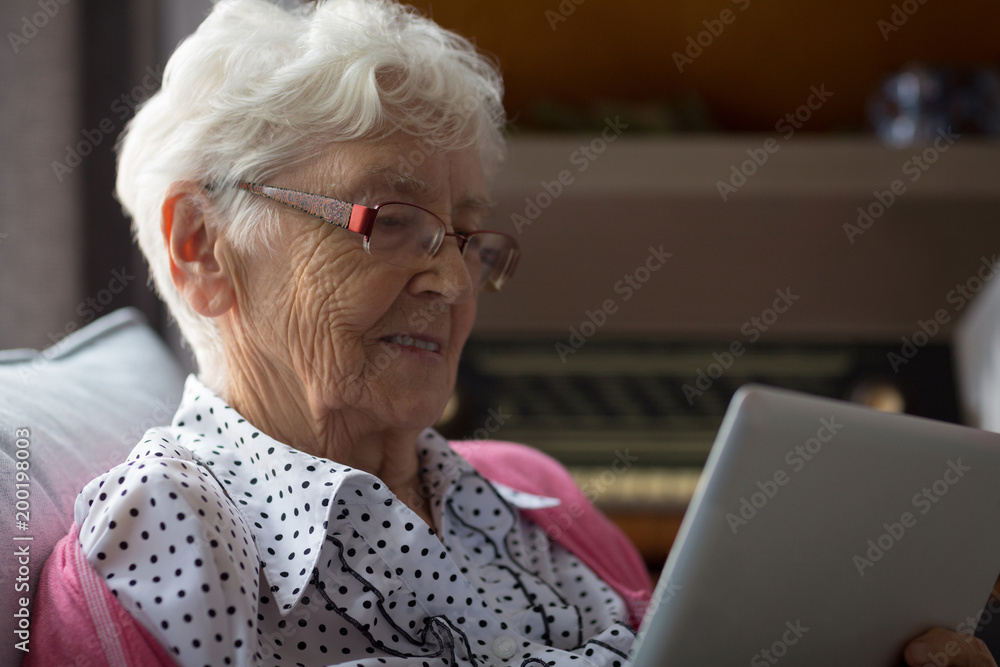 Senior woman using digital tablet while sitting at home Senior woman using digital tablet while sitting at home