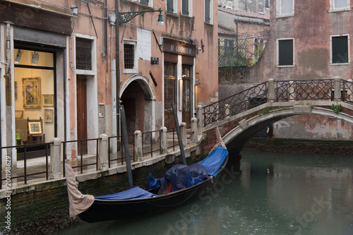 A venitian street canal with bridge and boats in Italy