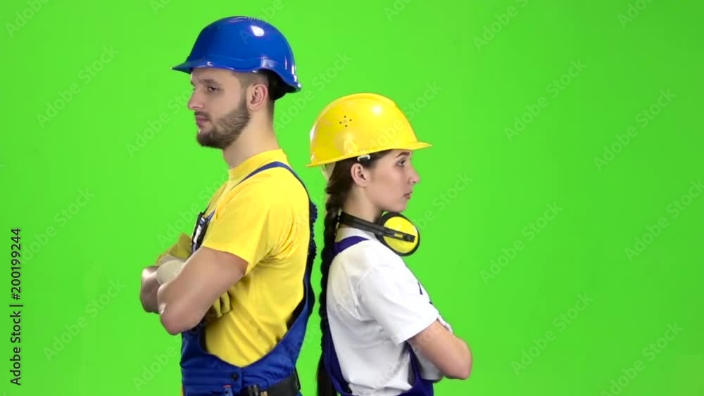 Two builders stand back to back and point with their fingers straight. Green screen. Slow motion Two builders stand back to back and point with their fingers straight. Green screen. Slow motion