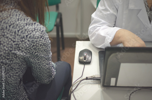 The girl undergoes a medical examination at a doctor reception for the diagnosis of health. The doctor conducts diagnostics of the patient with the help of computer equipment.