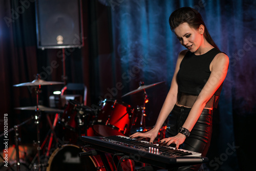 Woman playing keyboard on dark stage