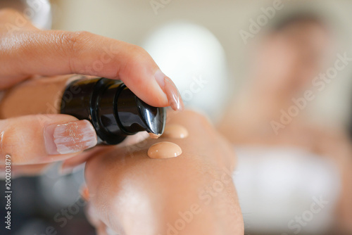 Asian woman applying foundation on her face for beauty.
