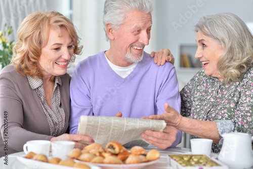 Happy senior people drinking tea and reading newspaper