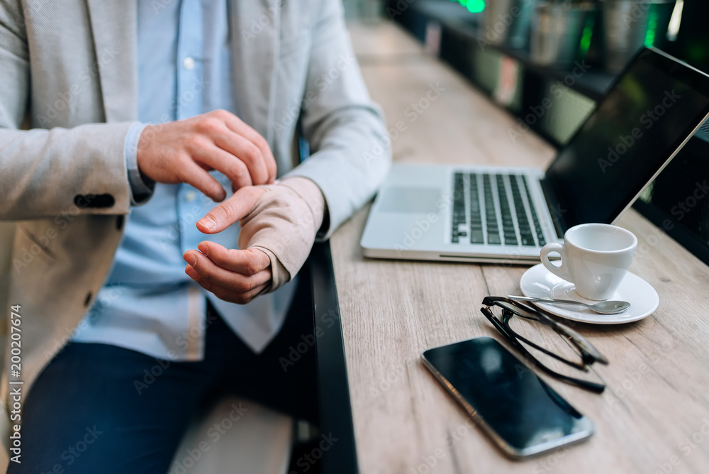 © bnenin - Close-up image of a men with bandaged hand sitting in the cafe in front of a laptop computer. © bnenin - Close-up image of a men with bandaged hand sitting in the cafe in front of a laptop computer.