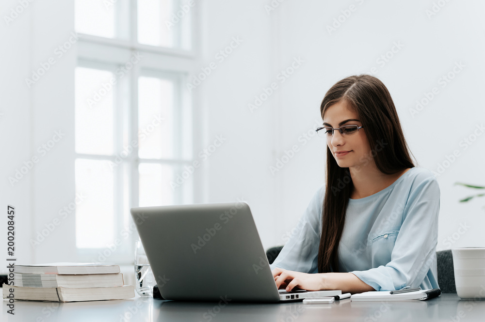 Portrait of young businesswoman typing on laptop while sitting at her workplace Portrait of young businesswoman typing on laptop while sitting at her workplace