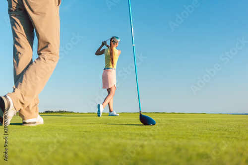 Low-angle full length view of a female professional golfer hitting a long shot, during a challenging matchplay game for two players outdoors in a sunny day