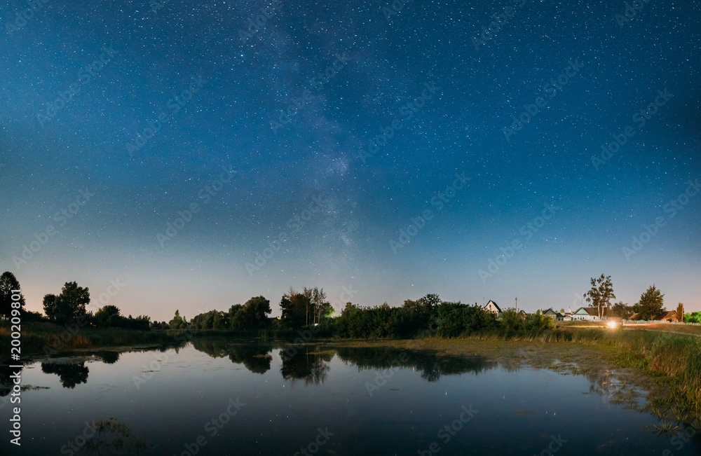 Night Starry Sky With Milky Way Galaxy Above Russian Village. Night Glowing Night Starry Sky With Milky Way Galaxy Above Russian Village. Night Glowing