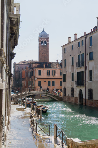 Flooded Venitian street with bridge, water canal, and bell tower