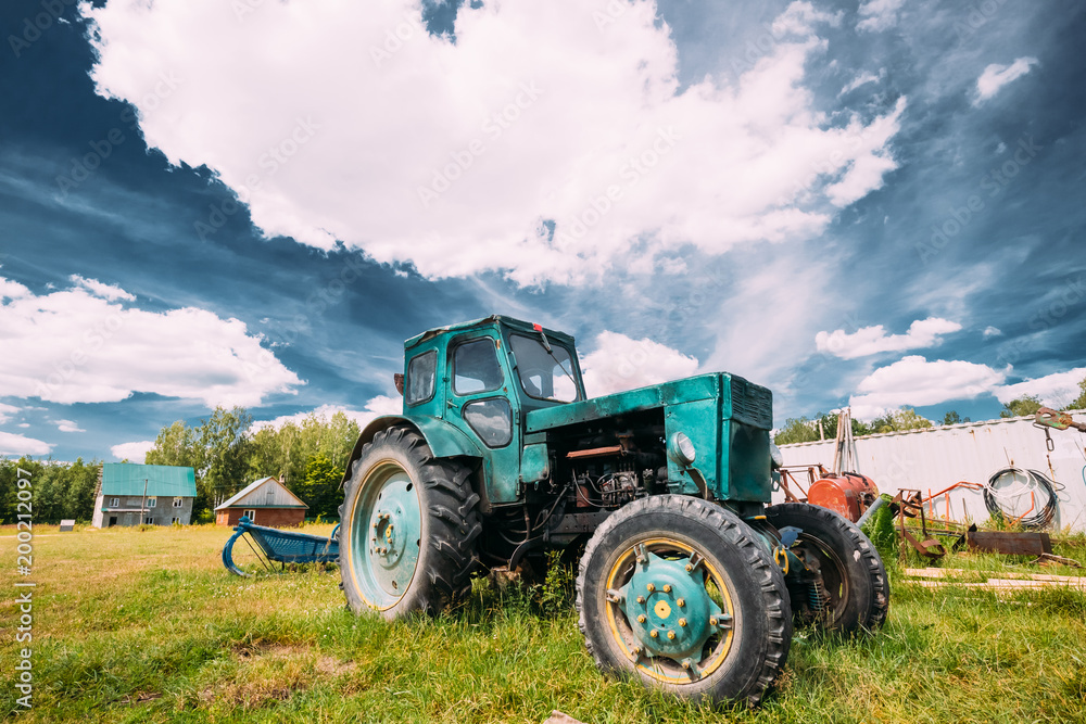 Old Tractor Parking In Backyard In Summer Sunny Day. Special Agricultural Equipment. Old Tractor Parking In Backyard In Summer Sunny Day. Special Agricultural Equipment.