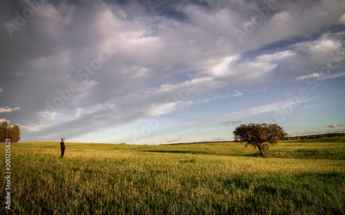 Lonely person in the middle of the pasture of Extremadura under a cloudy sky