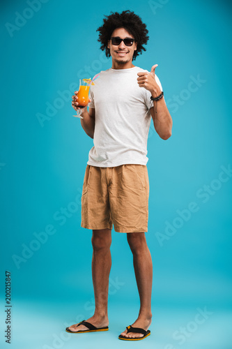 Handsome young african curly man holding cocktail showing thumbs up.