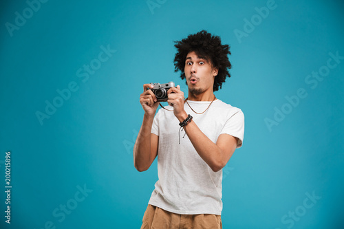 Shocked young african curly man photographer