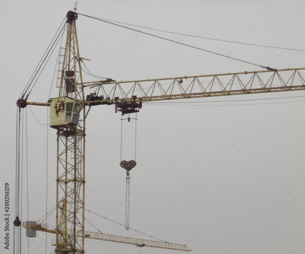 Construction cranes against the gray sky. Industrial constrcution cranes. Abstract background with construction cranes