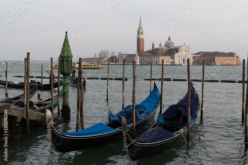 Parked covered gandolas on a pier at the sea with view on the San Giorgio Maggiore cathedral