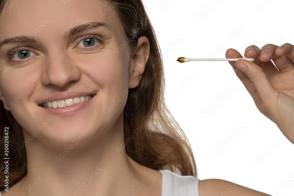Young beautiful brunette girl cleans the ears with chopsticks with cotton wool and is surprised to get a lot of yellow earwax Young beautiful brunette girl cleans the ears with chopsticks with cotton wool and is surprised to get a lot of yellow earwax