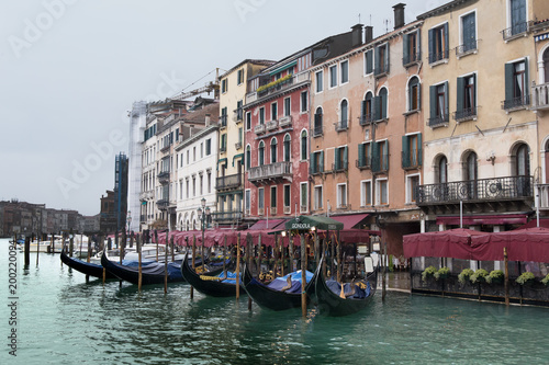 Gondolas on a Grand Canal pier in front of the old Venice restaurant and residential buildings