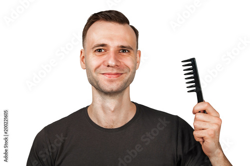 Young man with smile holding hair comb. Isolated on white.