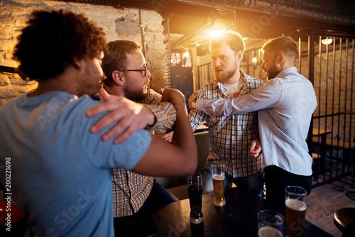Photography Friends preventing fighting of two angry guys in the bar.