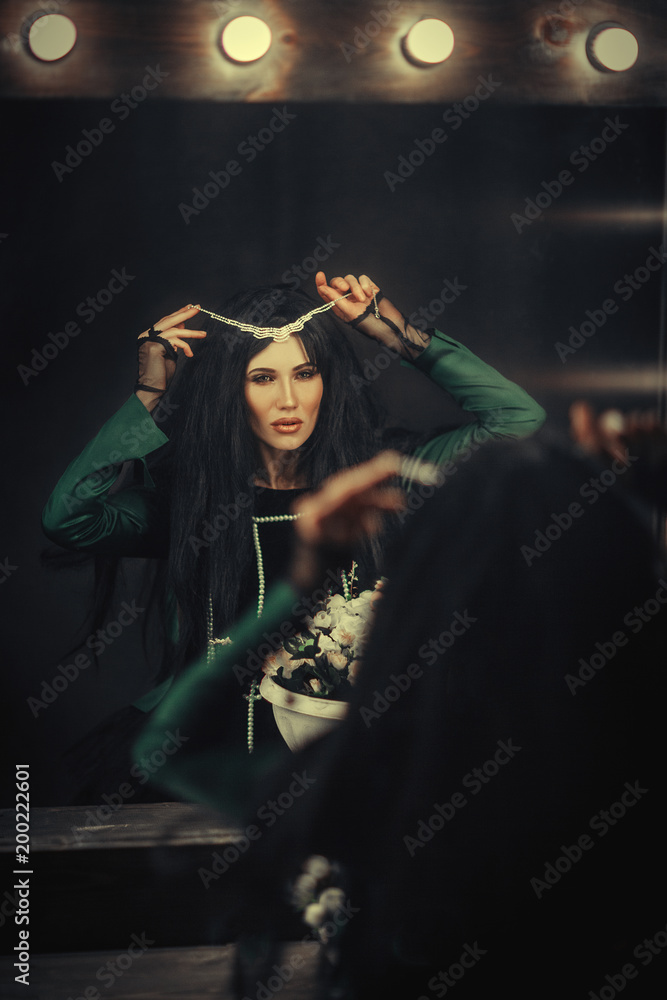 Dark haired model is posing in a dark studio with a mirror Dark haired model is posing in a dark studio with a mirror