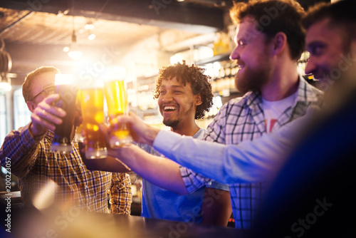 Canvas Print Handsome smiling young afro-american man clinking beer glasses in the pub
