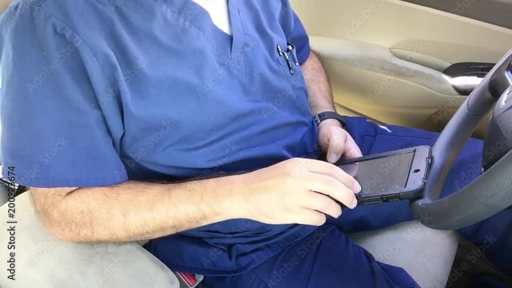 Male home health nurse working on computer in car after exam on patient Male home health nurse working on computer in car after exam on patient