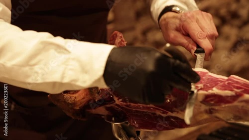 Professional hands slicing iberico spanish ham in a restaurant or event.