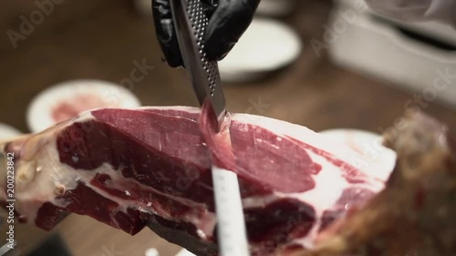 Professional hands slicing iberico spanish ham in a restaurant or event.