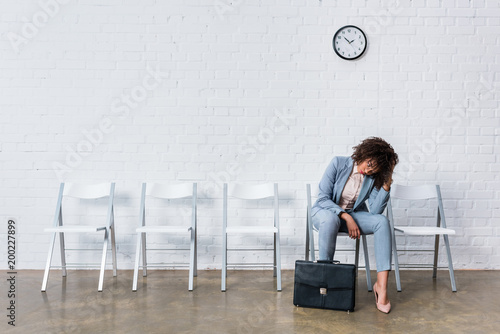 Tired female candidate with briefcase waiting for interview