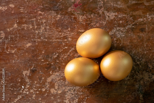 Golden eggs on a rustic wooden background